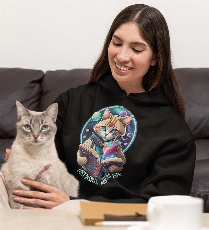 Woman with cat wearing hoodie with cat reading book